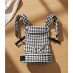 Houndstooth patterned baby carrier with padded straps on wood floor