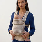 Mother wearing the Tiny Table Houndstooth ergonomic baby carrier with her newborn